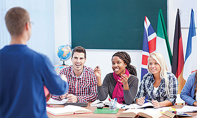Adult students sitting in a classroom interacting with their teacher