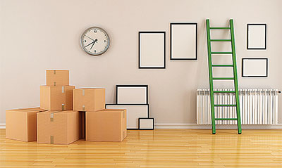 A room in a house with moving boxes laying around, and empty picture frames on the wall