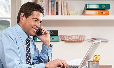 Businessman on his mobile phone whilst working on his laptop